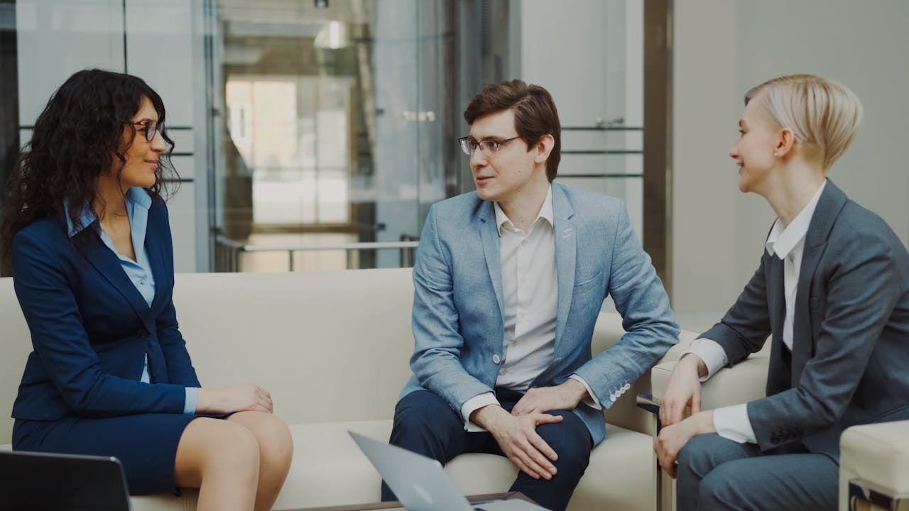 Mastering the First Impression: Your intriguing post title goes here Three professionals in a business meeting, discussing ideas in a modern office environment.